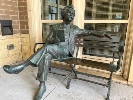 Sculpture of Mark Twain sitting on a bench with an open book