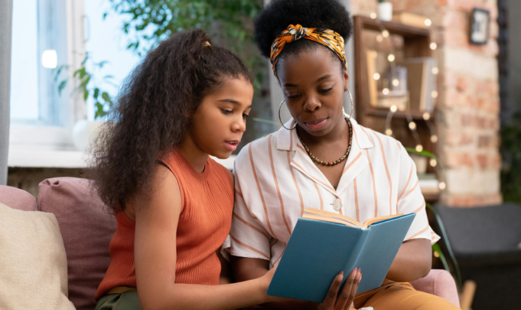 Woman and tween girl sitting together with an open book