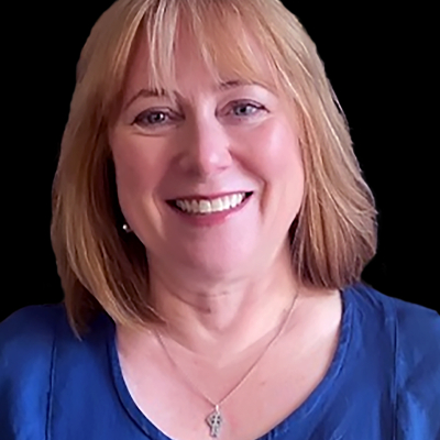 Professional photo of a person with a blue shirt on. She is smiling at the camera.